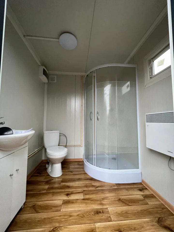 Contentor sanitário de 2x2 m com chuveiro e reservatório.